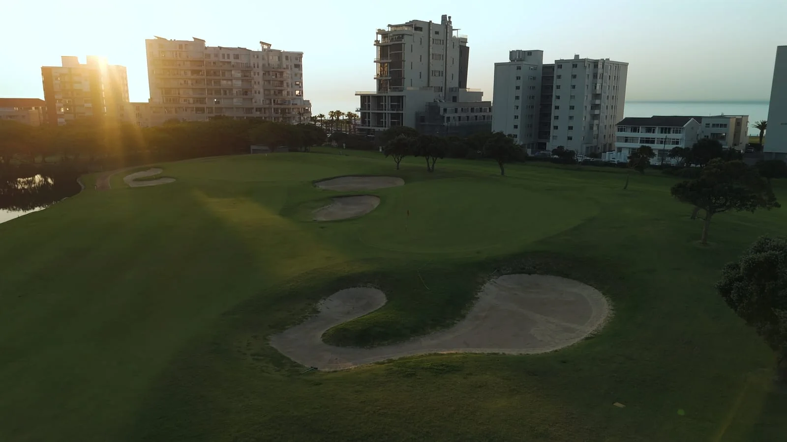The sun low over a green and its bunkers